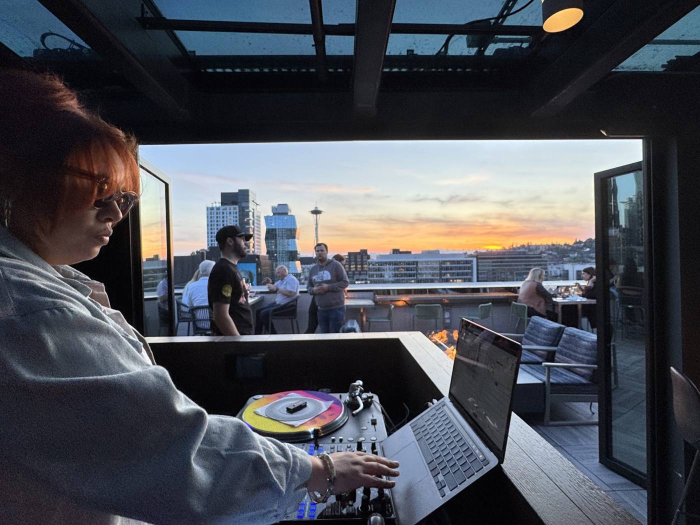 Lady CoCo DJing at Altitude Sky Lounge at sunset, with the Space Needle behind