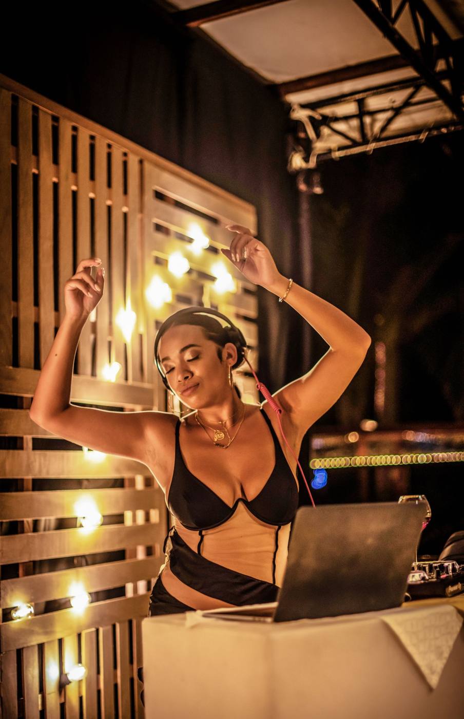 Lady CoCo performing, arms raised, under warm string lights